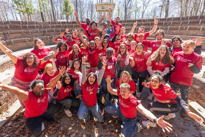 A group of students wearing red leadership t-shirts gather in an amphitheater.